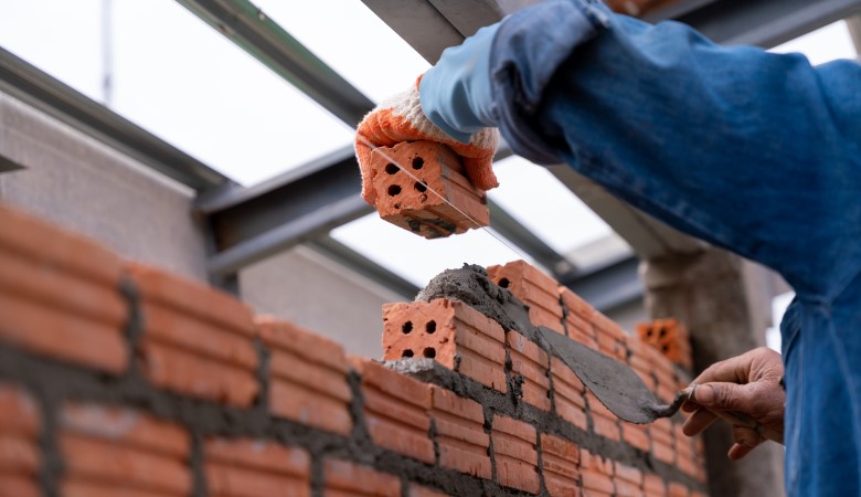 Personne qui construit un mur en brique