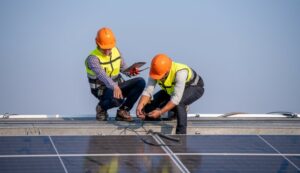 deux hommes en train d'installer des panneaux solaires sur un toit