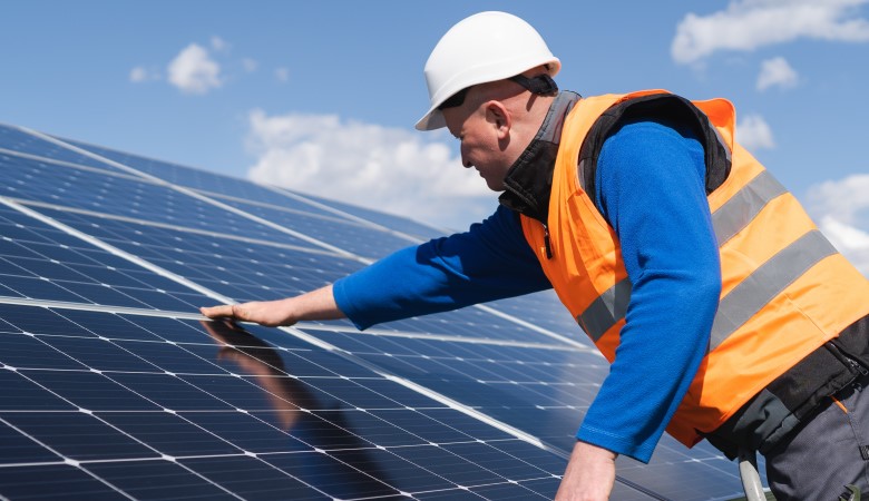 Un homme en train de poser des panneaux solaires sur un toit