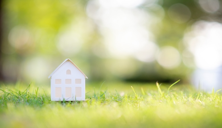 Petite maison blanche factice en bois sur du gazon.