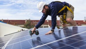 travailleur qui fixe un panneau solaire sur un toit